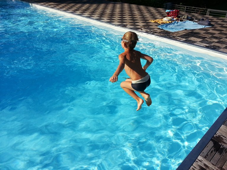 Kind springt in ein Schwimmbecken