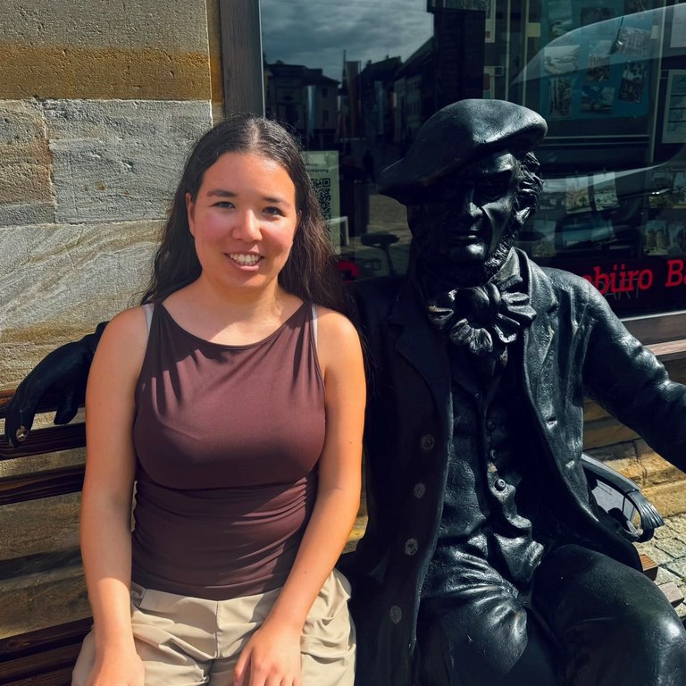 Mädchen auf einer Bank mit Statue nebendrann