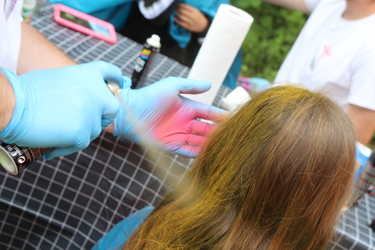 einem Maedchen wird Farbe ins Haar gesprueht