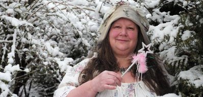 Frau mit Zauberstab in der Hand vor verschneiten Baeumen
