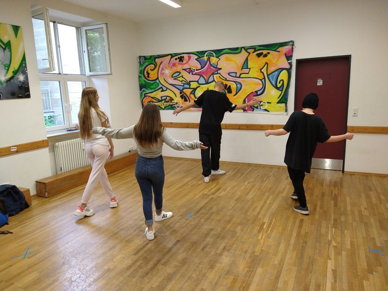 Vier Personen, die in einem Raum gegen die Wand tanzen  