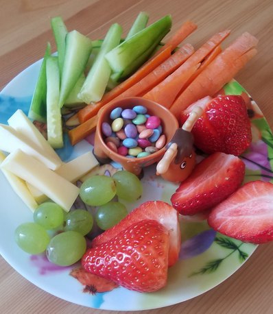 Teller mit verschiedenem Obst, Gemüse und Süßigkeiten