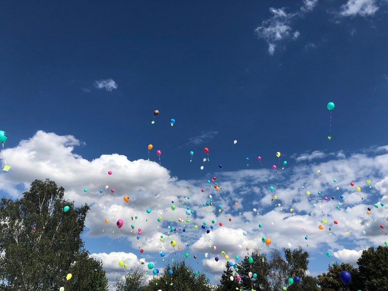 Luftballons, die in den blauen Himmel mit weißen Wolken aufsteigen