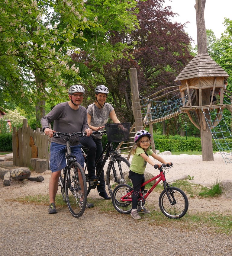 Familie mit dem Rad vor einem Kletterhaus  