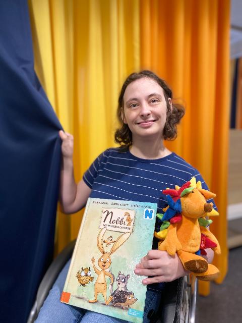 Frau mit Buch und Stofftier in der Hand