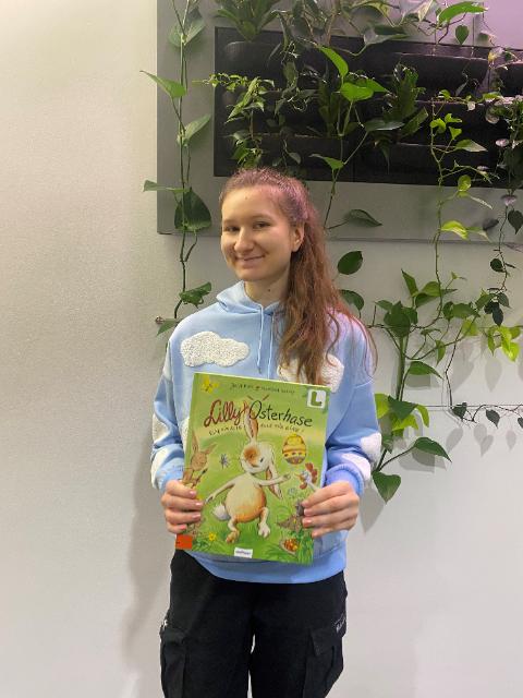 Frau stellt ein Buch vor mit dem Titel Lilly Osterhase