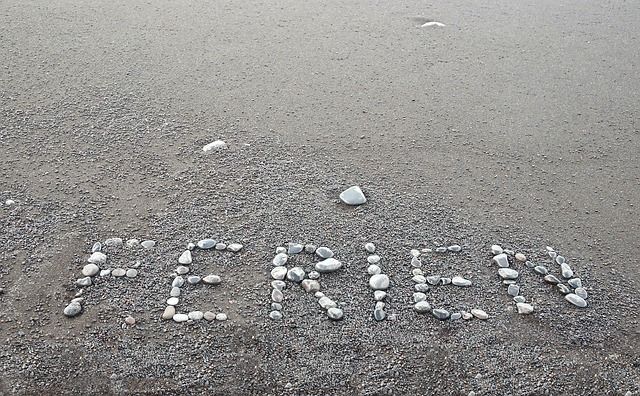 Das Wort Ferien in den Sand mit Steinen geschrieben