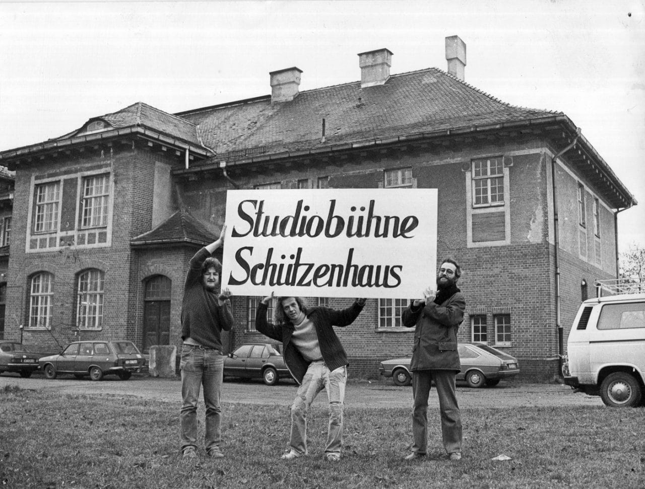 drei Personen halten ein Banner hoch mit der Aufschrift Studiobuehne Schuetzenhaus