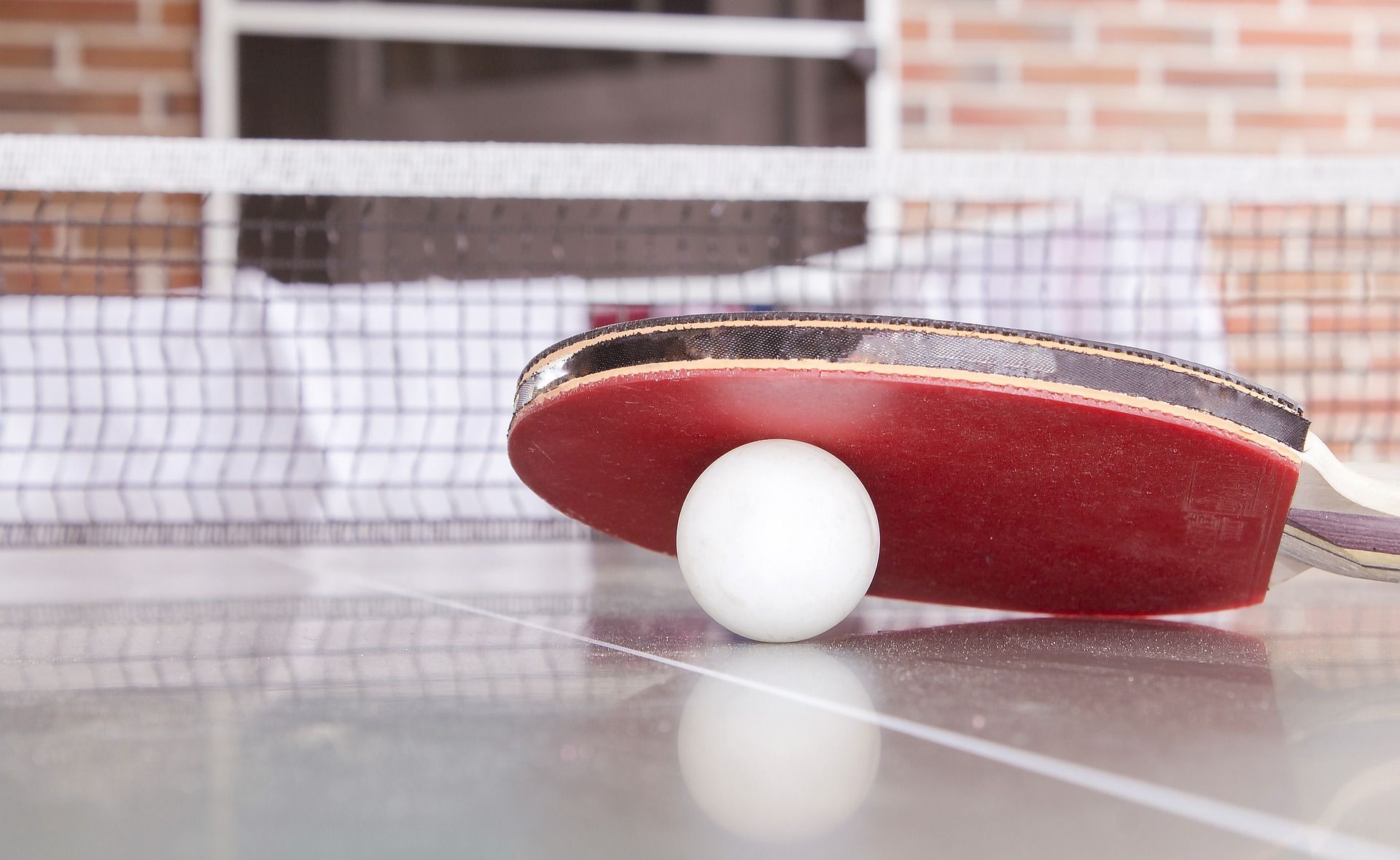 Tischtennisschlaeger auf einer Platte, darunter liegt ein Ball